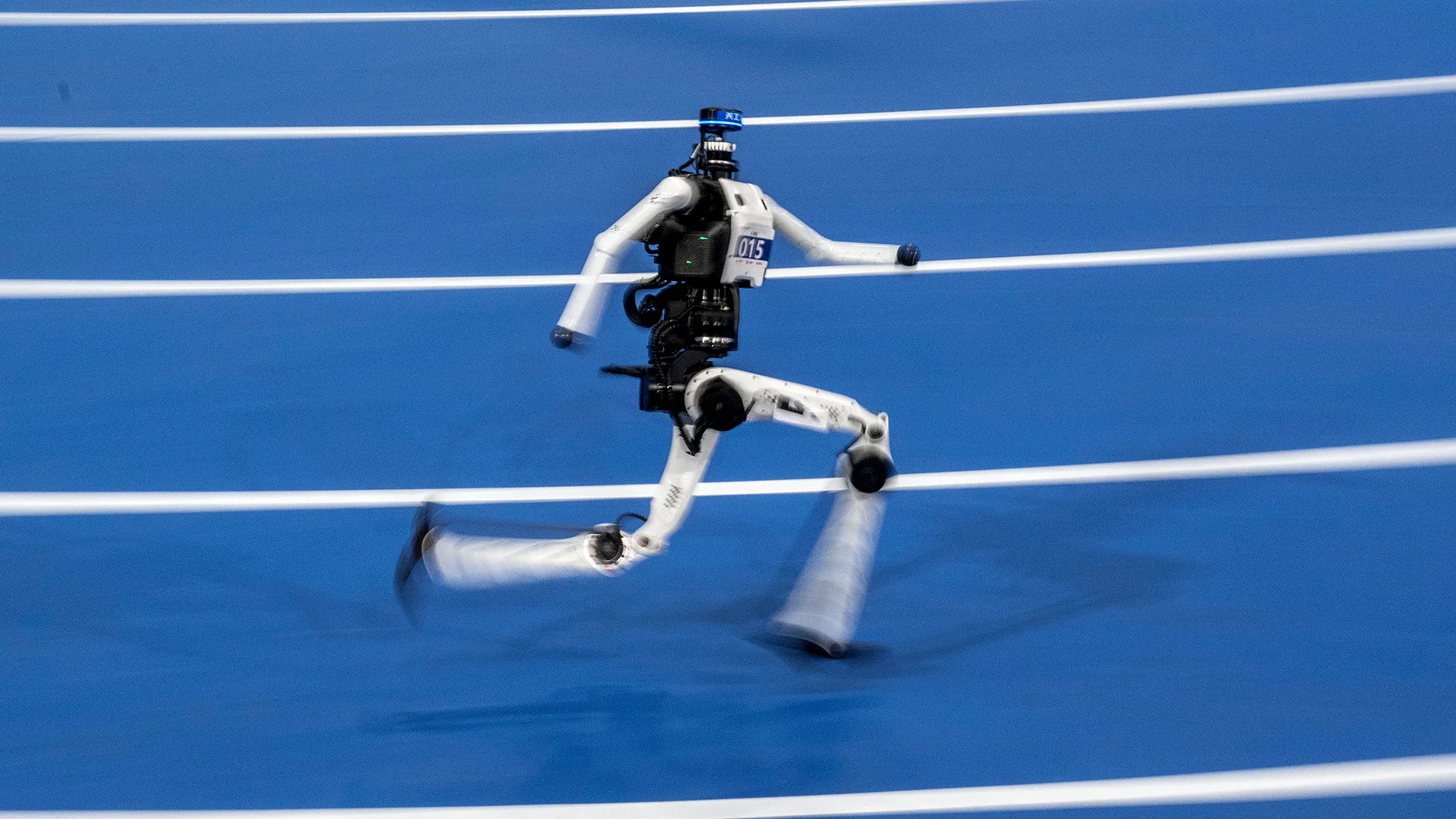 A black-and-white humanoid robot sprints on a blue track.